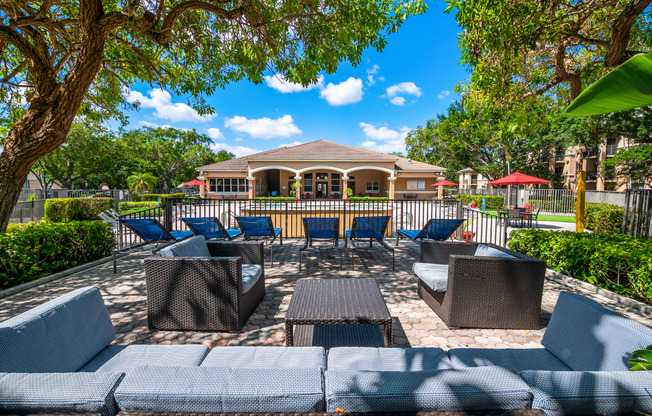 a patio with chairs and tables and a house in the background