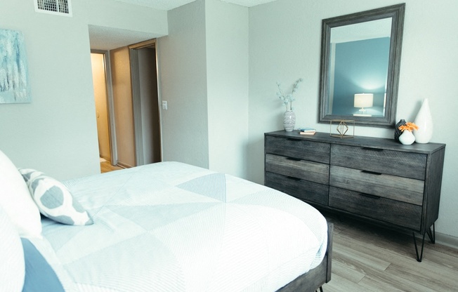 a bedroom with a bed and a dresser with a mirror