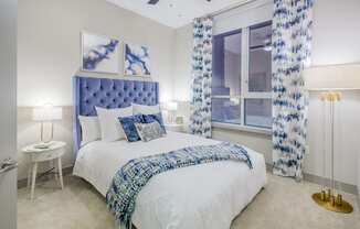 a bedroom with a bed and a window with blue and white curtains