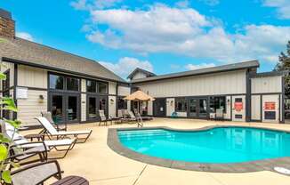 a swimming pool with chaise lounge chairs and umbrellas in front of a building