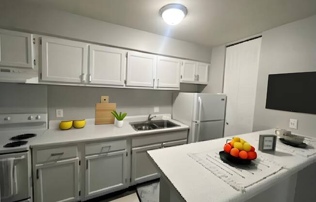 a kitchen with white cabinets and a counter with a bowl of fruit