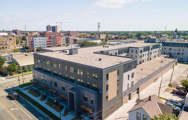a large gray building with a gray roof and a city in the background at The Landing at 1001 NP, Fargo, North Dakota 58102