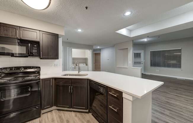 a kitchen with a white counter top and black appliances at Ashford Belmar Apartments, Lakewood