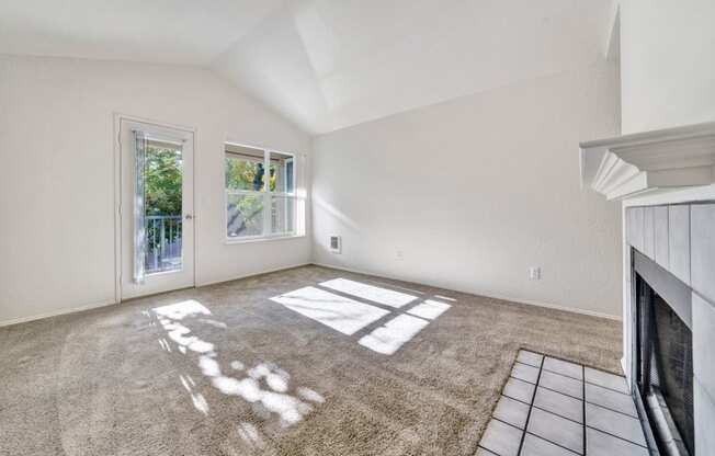 an empty living room with a fireplace and a window