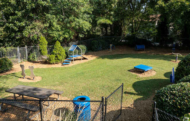 A backyard with a blue trash can and a blue bench.