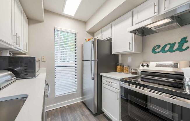 A kitchen with a refrigerator, oven, and microwave.