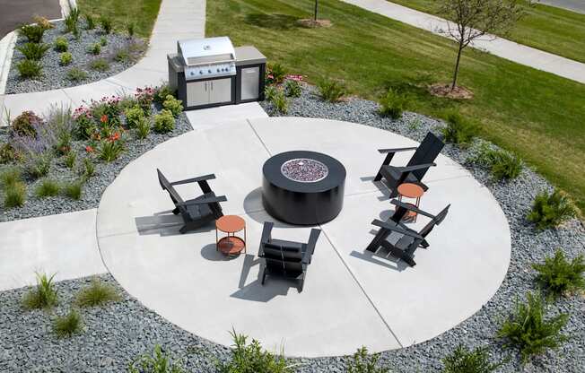 a fire pit and seating area on a concrete patio in a park