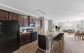 A modern kitchen with dark wood cabinets and a black refrigerator.