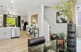 a living room with a glass table and a kitchen