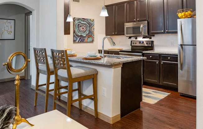 A kitchen with a white island and wooden chairs.
