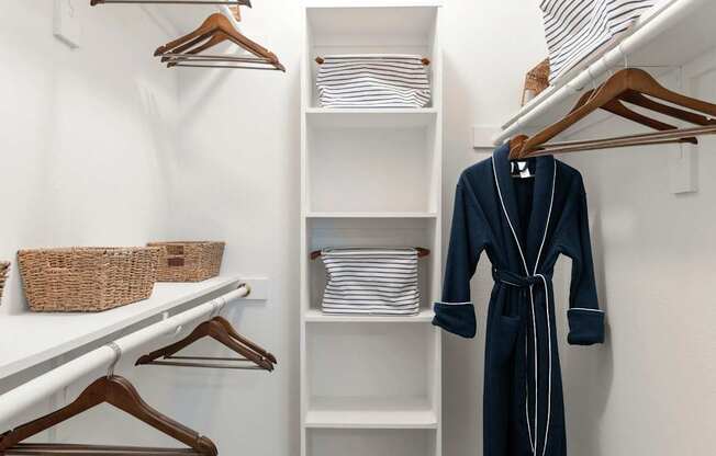 A white closet with a blue robe hanging on a hanger.