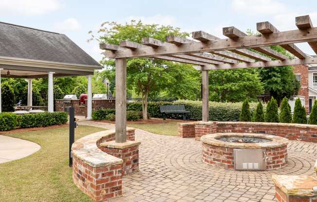 a brick fire pit and pergola in the backyard of a home