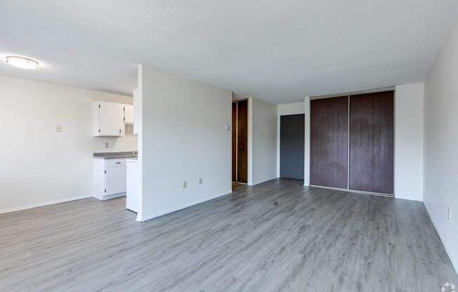 A spacious room with wooden flooring and white walls.