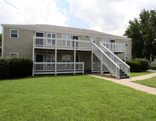 the back of an apartment building with a porch and a lawn