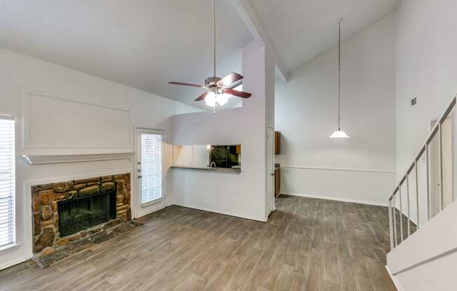 an empty living room with a fireplace and a ceiling fan