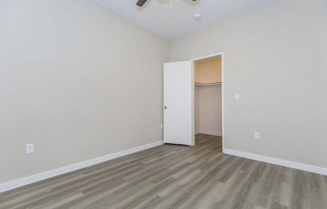 A room with a ceiling fan and a doorway leading to another room.