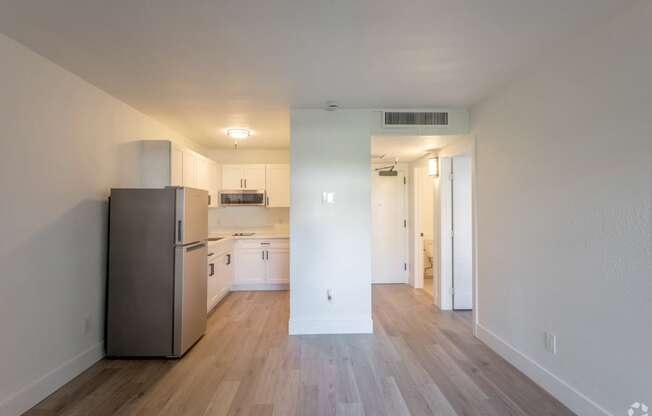 an empty apartment with a refrigerator and a kitchen