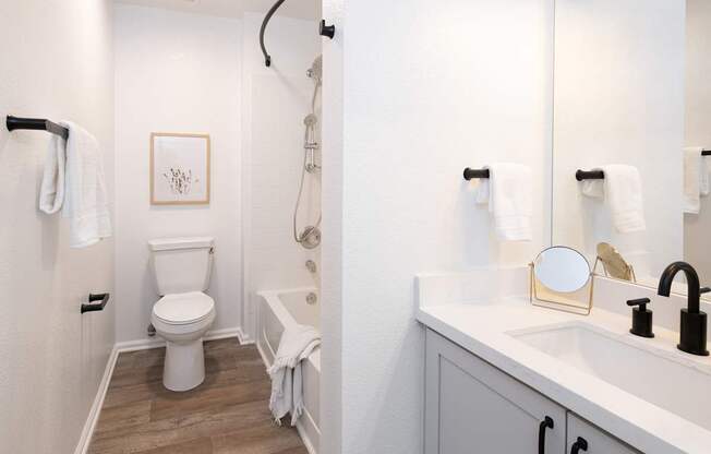 A white toilet is in a small bathroom with a white sink.