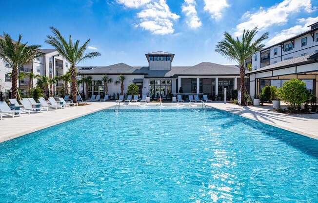 A large swimming pool in front of a building with palm trees.
