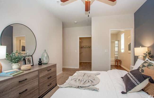A bedroom with a bed, dresser, mirror, and ceiling fan.