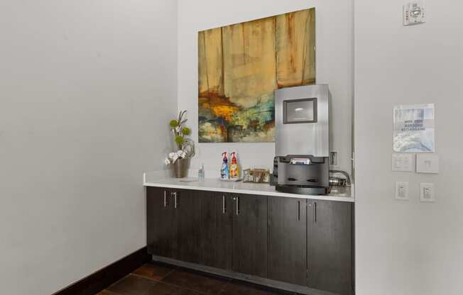 an office with a coffee machine and a counter with a painting on the wall