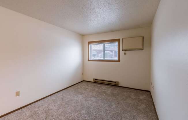 the living room of an apartment with carpet and a window. Fargo, ND Parkwood