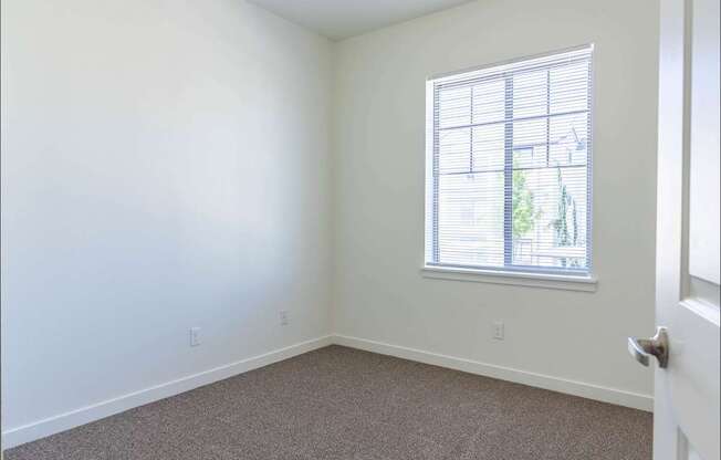 A room with a carpeted floor and a window with blinds at Riverplace Apartment Homes, Independence, 97351