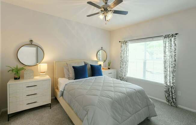 A bedroom with a bed, nightstand, and window.