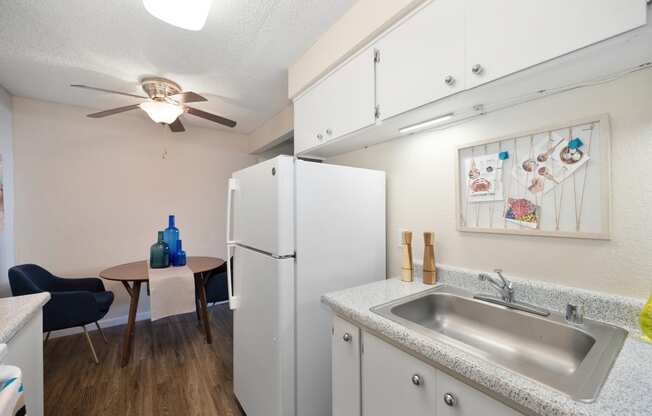 a kitchen with a sink and a refrigerator and a ceiling fan