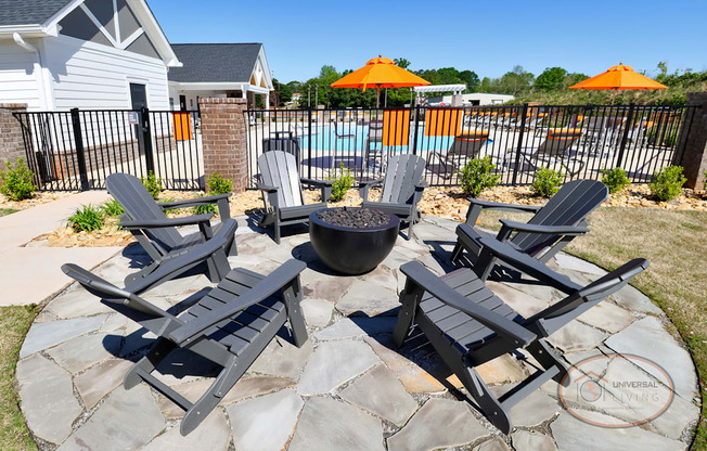 An outdoor fire pit surrounded by Adirondack chairs on a stone pad..