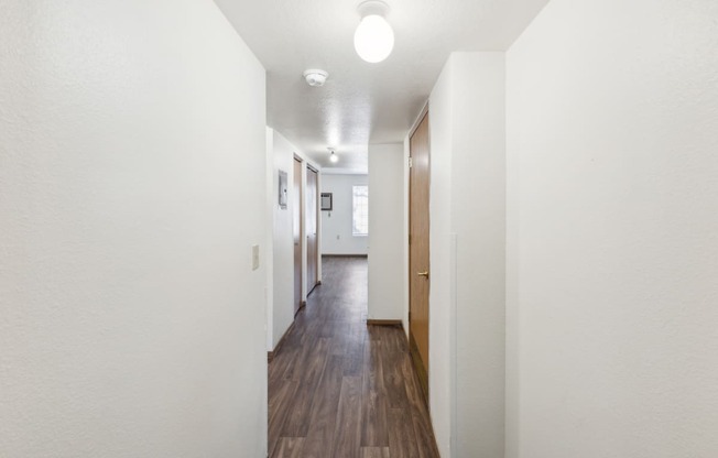 a long hallway with wood floors and white walls