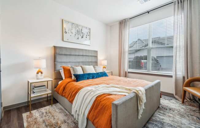 a bedroom with a large window and a bed with an orange blanket