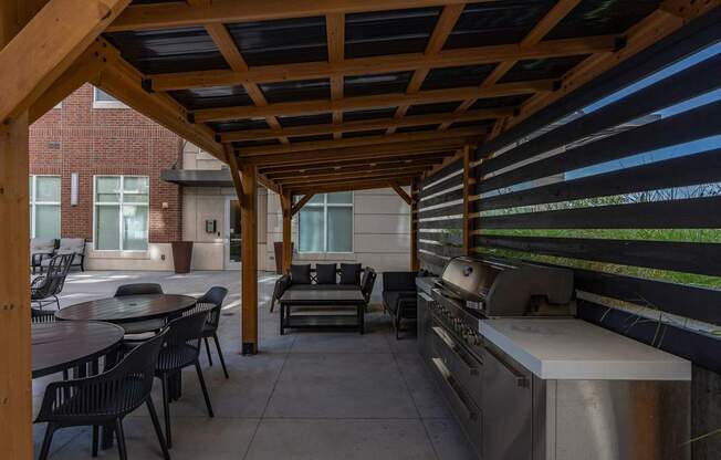 a covered patio with a grill and tables and chairs