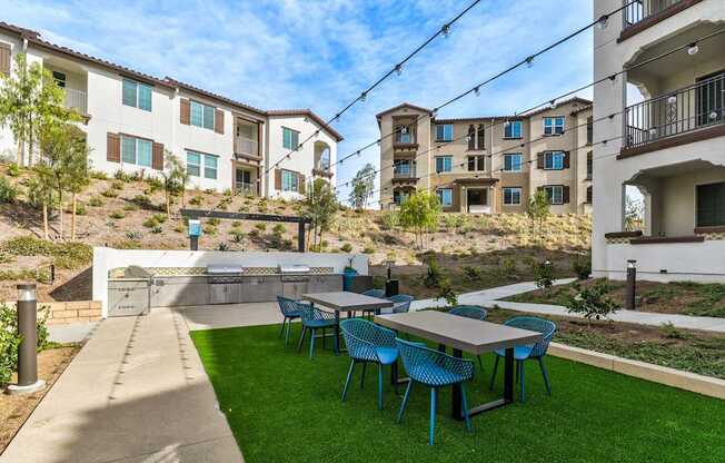 A patio with blue chairs and a table is in front of apartment buildings.