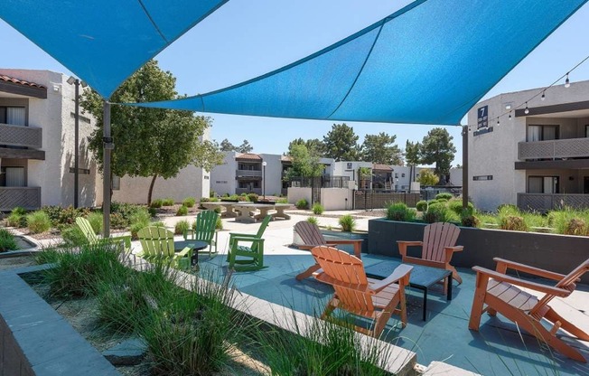 A blue shade structure is over a patio with chairs and tables.