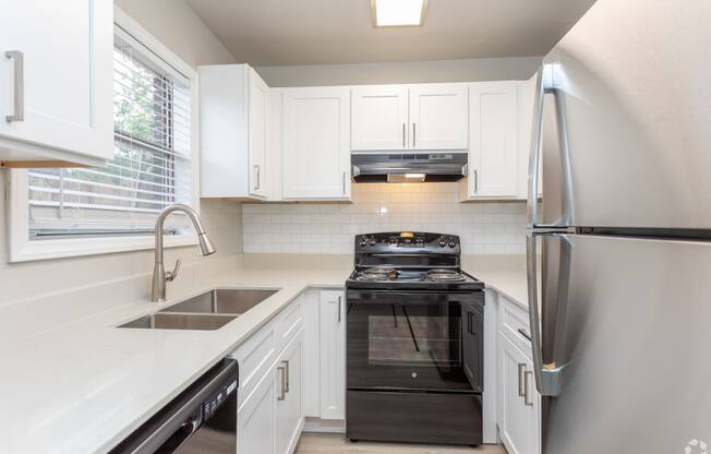 a kitchen with white cabinets and black appliances and a stainless steel refrigerator