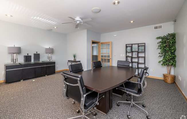 A conference room with a large table surrounded by chairs.