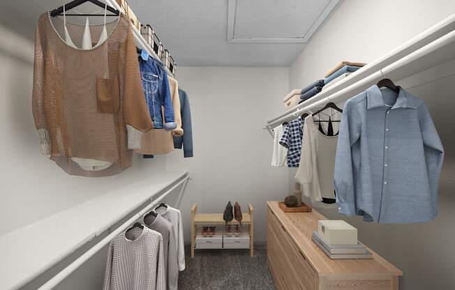A walk in closet with clothes hanging and a bench underneath.
