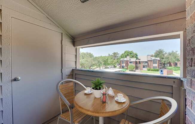 A small table with two chairs is set up on a balcony.