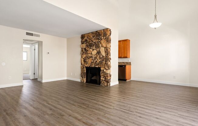 A room with a stone fireplace and wooden floors.
