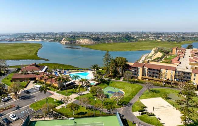 an aerial view of a resort with a tennis court and a lake