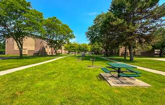 Expansive green space with picnic area at Woodland Villa Apartments in Westland, MI.