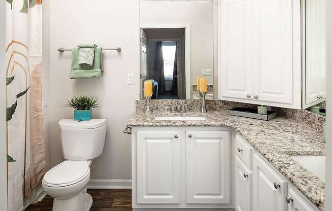 A white toilet is in a bathroom with a counter top.