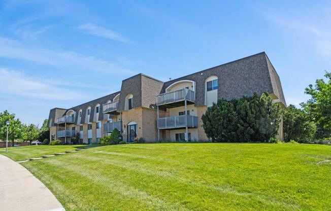 a large brick apartment building with a green lawn