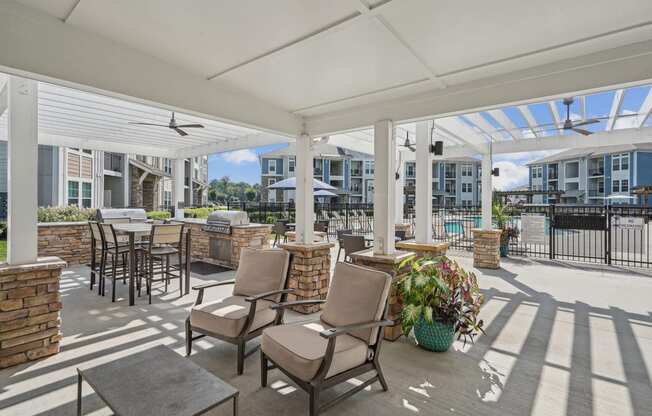 a covered patio with chairs and tables and a building in the background