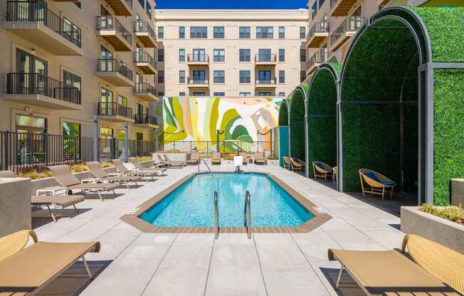 A pool surrounded by lounge chairs and umbrellas.