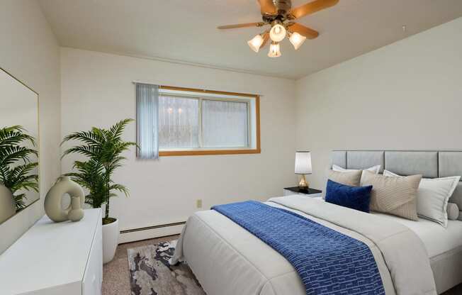 a bedroom with a large bed and a ceiling fan. Fargo, ND Country Club Apartments.