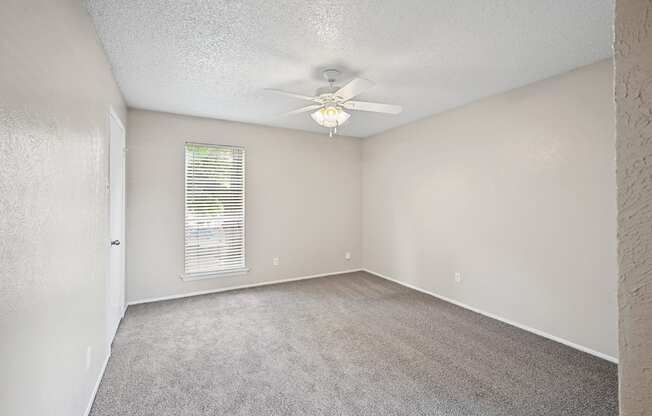 an empty bedroom with a ceiling fan