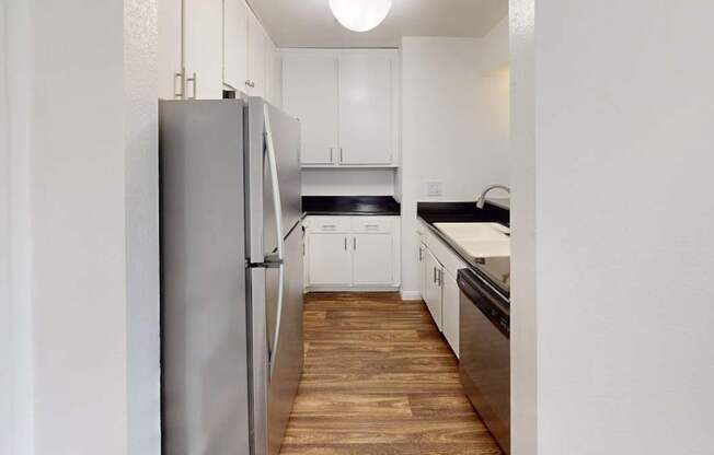 A kitchen with a refrigerator and wooden floors.