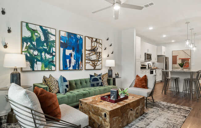A living room with a green couch, a coffee table, and a painting on the wall.